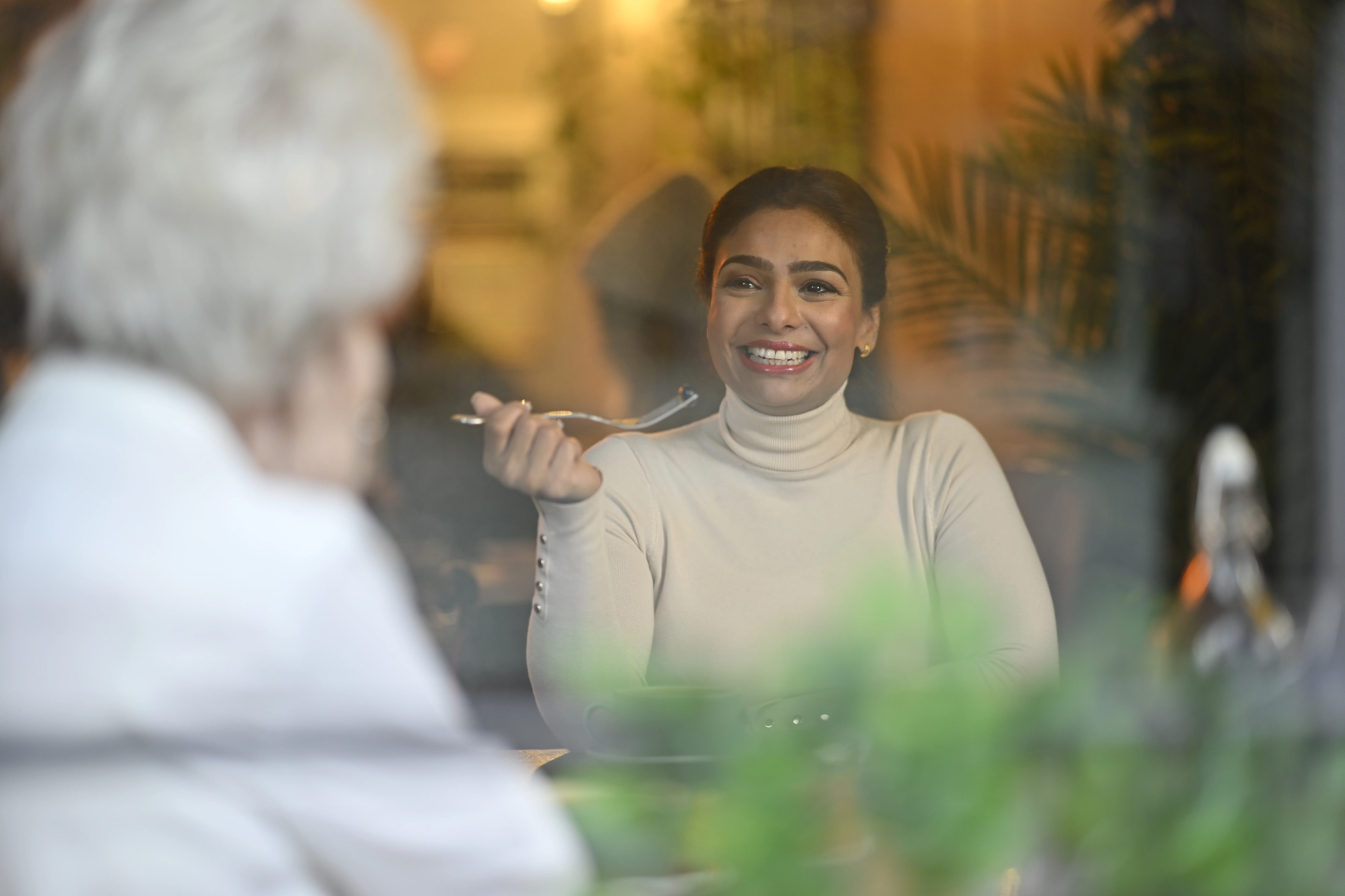a woman smiling while holding a spoon