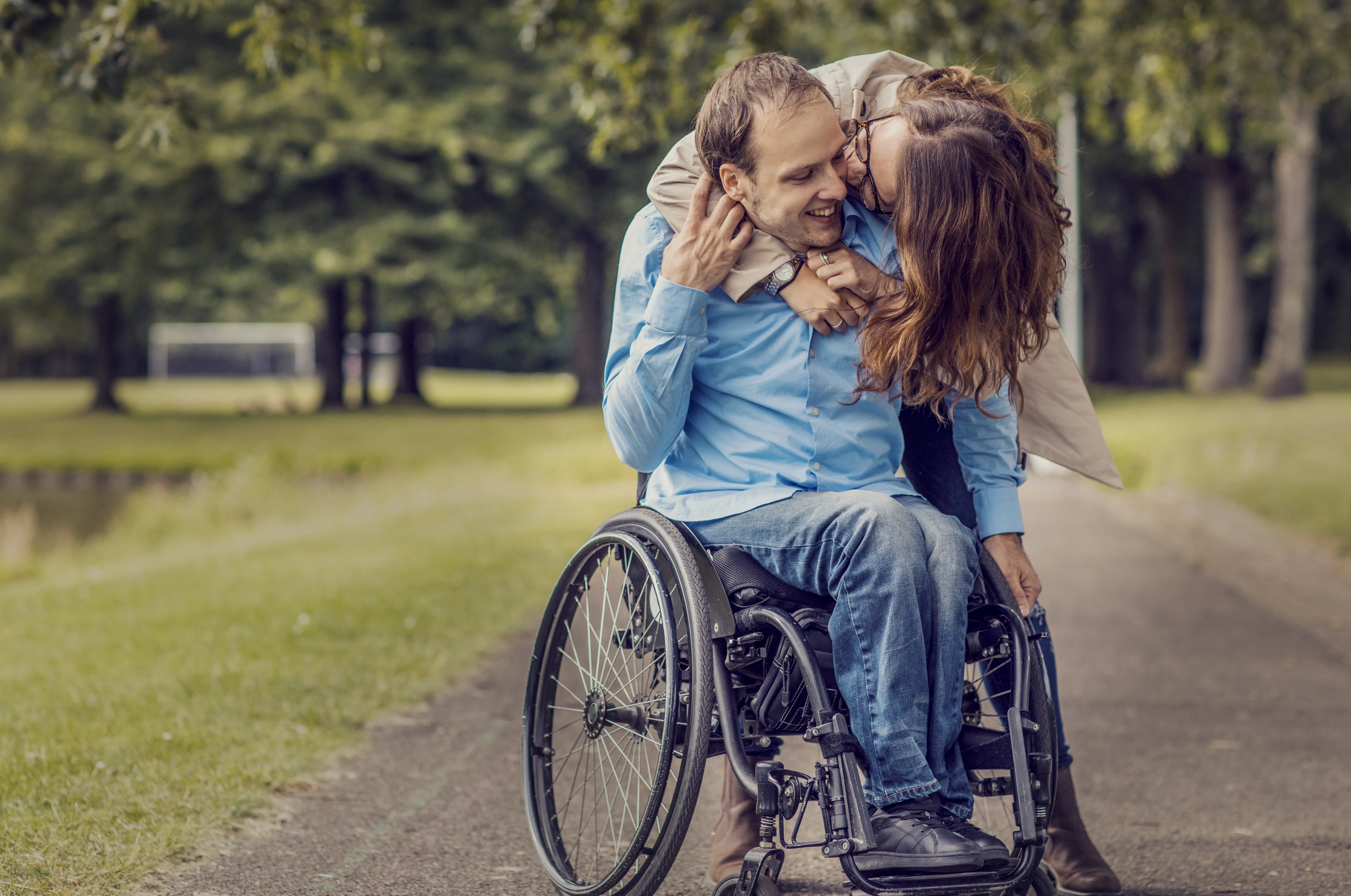Un hombre y una mujer besándose en una silla de ruedas