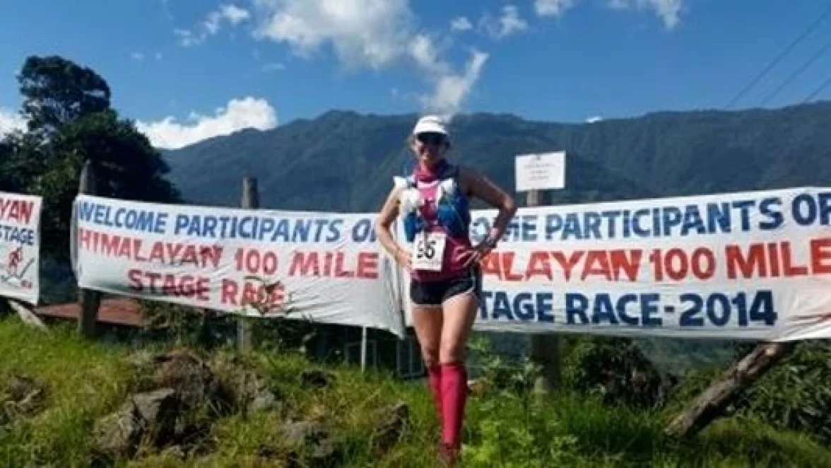 En kvinna står bredvid en banderoll med texten "VÄLKOMNA DELTAGARE I HIMALAYAN 100 MILE ETAPP RACE - 2014".