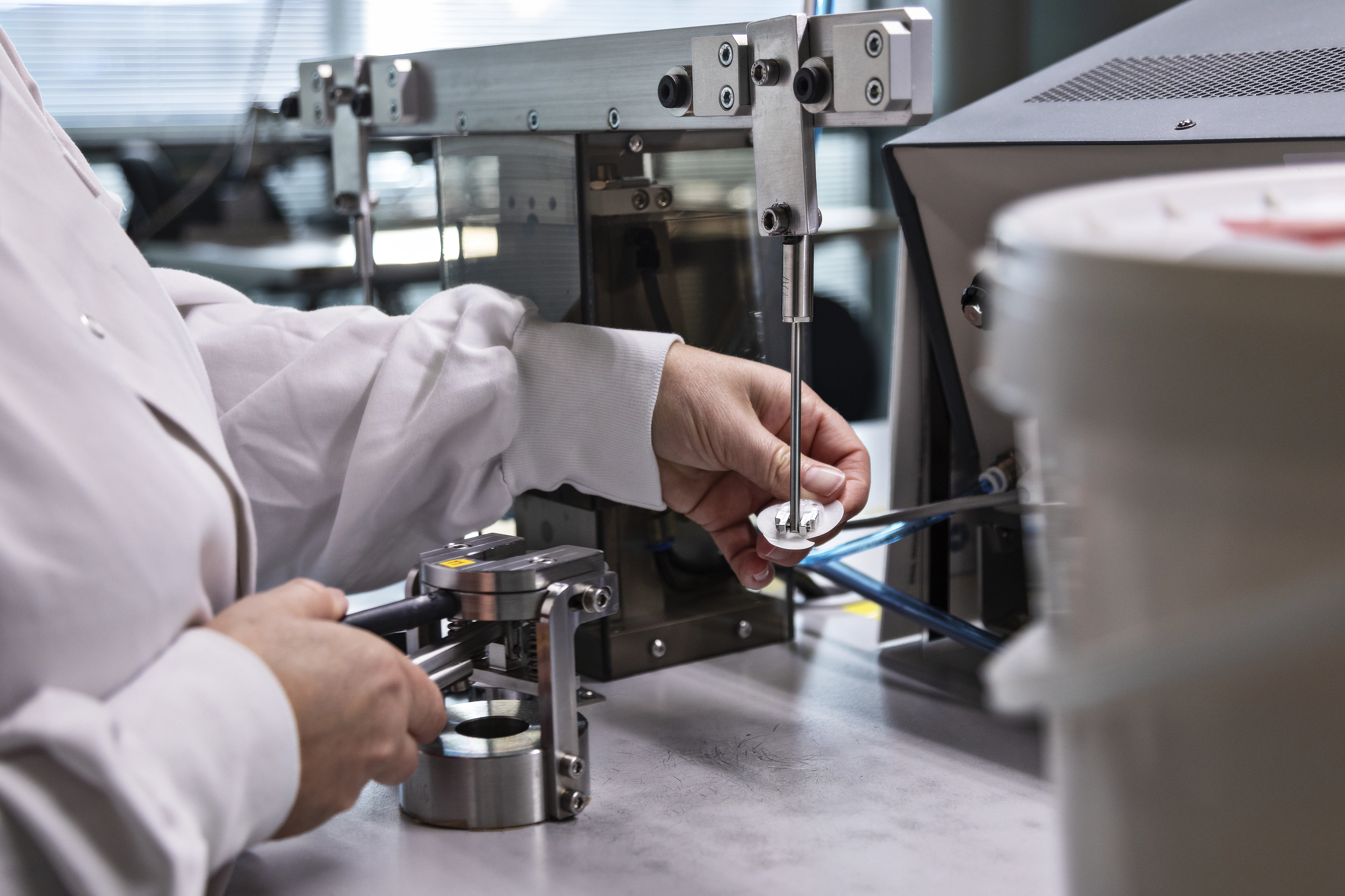 een persoon in een laboratoriumjas die aan een machine werkt