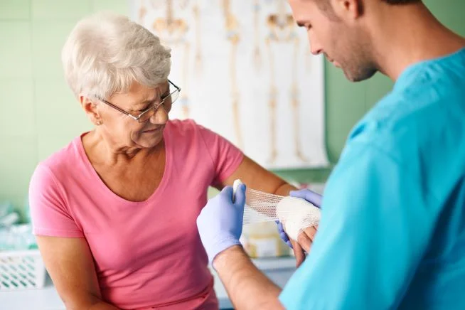 Ein Pfleger verbindet den Arm einer Patientin. 